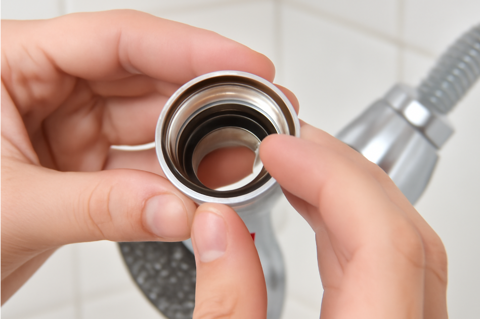 "Close-up of a person’s hands inspecting the O-ring and washers inside a shower head, ensuring proper installation for leak prevention." 