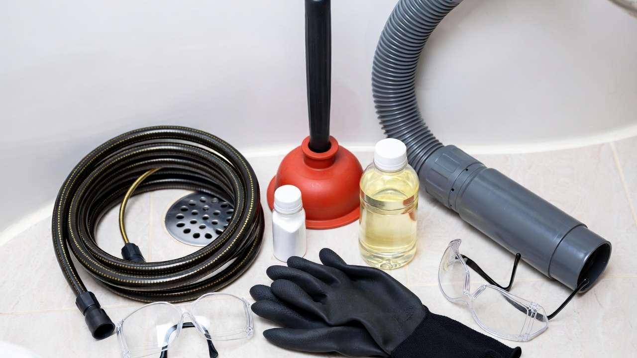 Essential tools for unclogging a shower drain clogged with hair, including snake and plunger.