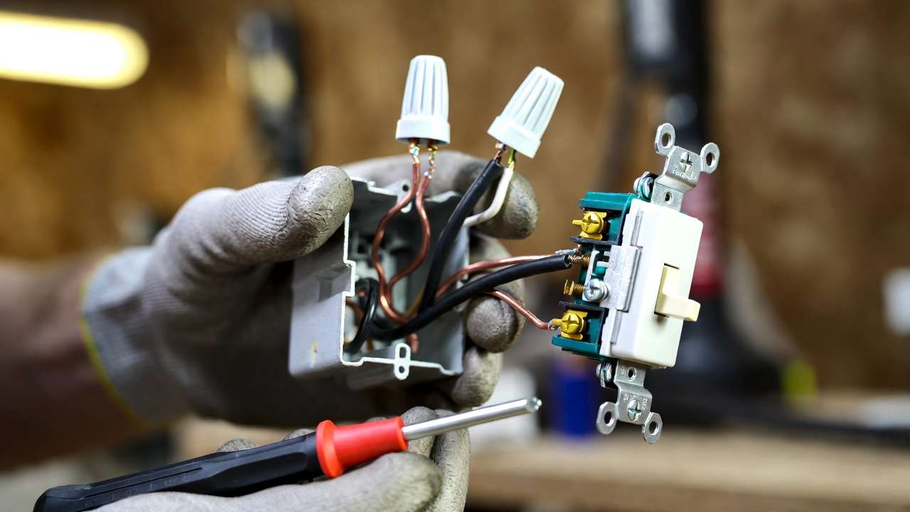Hands wiring a single-pole light switch safely with proper connections and tools.