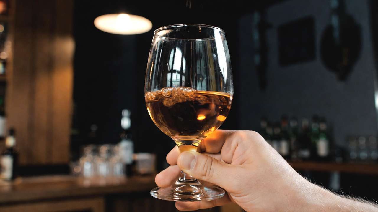 Hand swirling bourbon in stemmed glass for optimal aeration