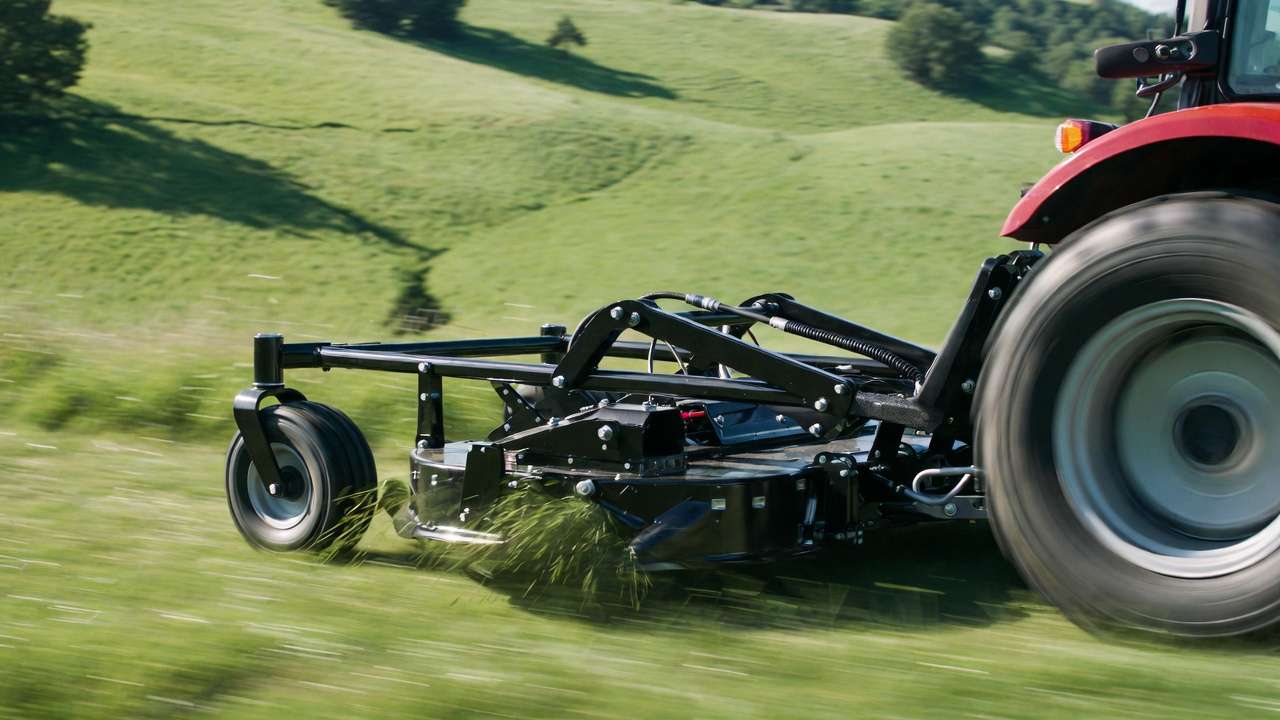 Pull behind mower floating deck in action on hillside showing anti-scalp wheels and linkage
