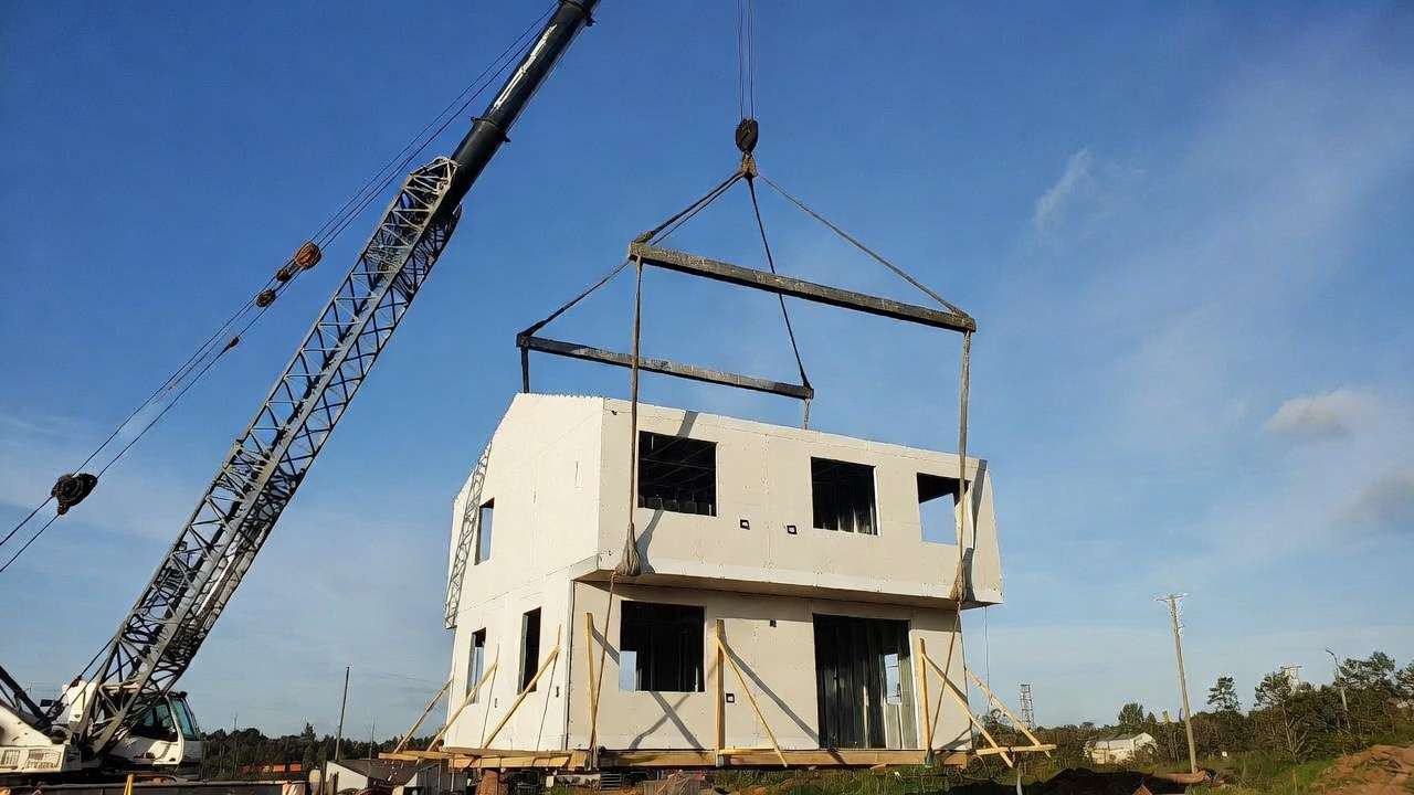 Crane lifting a two-story modular home section with spreader bar and bracing
Image 3